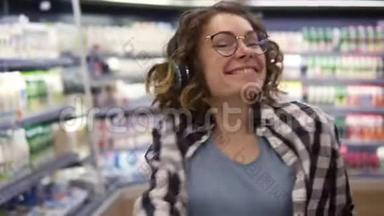 在超市：快乐的年轻女孩在超市的货架之间滑稽地跳舞。 穿着黑白衣服的卷发女孩